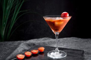Sopa de tomate fría española, gazpacho, hecha con tomate, pepino, pimiento, cebolla, ajo y aceite de oliva servida en copa de cóctel con tomates cherry sobre fondo negro