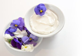 Obraz na płótnie Canvas Natural balm from viola or violet flowers in white bowls, cosmetics concept, white gray background with copy space, selected focus