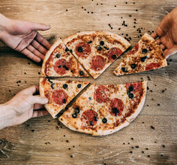 Slices of pepperoni pizza in hands. Group Of Friends Sharing