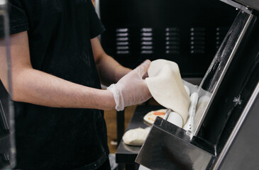 Pizzaiola straightens pizza dough in pizzeria