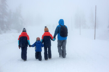 Sweet children, playing in the snowAdorable family with three children, having family time, walking together in deep snow in the mountains