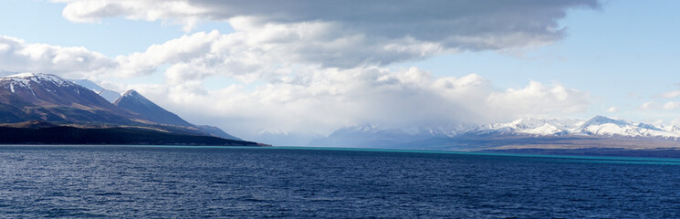 Lake Tekapo with nearby snow covered mountain peaks on a sunny day in the South Island of New...