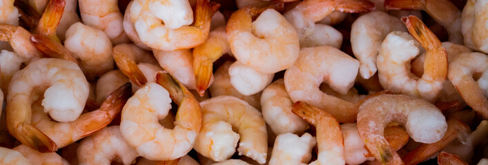 Close-up of a pile of frozen orange shrimps. Peeled shrimp, leaving only tails. Natural seafood background