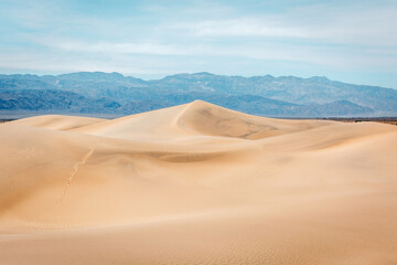 Contrasting light and shadows on sand dunes and mountains in Mesquite Flat, Death Valley National Park, California.
