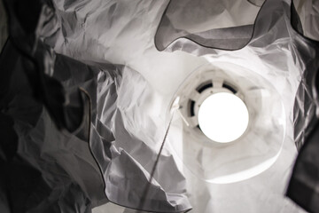 Abstract picture. Bottom view of the lamp made of crumpled paper with a burning light bulb inside