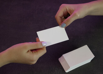 Business woman exchanging business cards. Close-up view of the hands. Gray stone background.