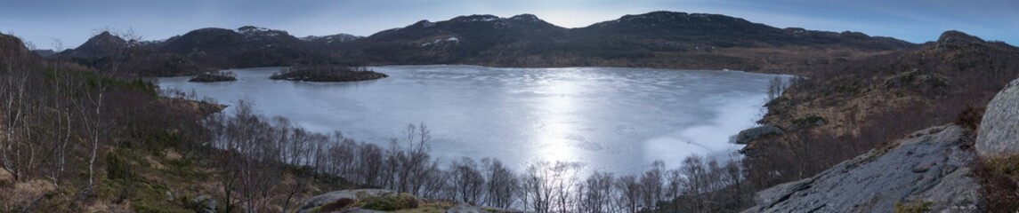 Fototapeta premium Hiker with Samoyed husky dog ​​looking at frozen lake and fjord in Rogaland Norway