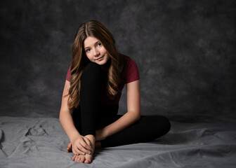 Beautiful tween girl sitting on floor, low key.