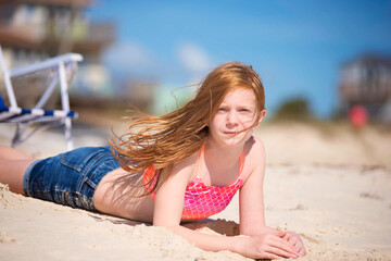Tween red haired girl in swimsuit on the beach.