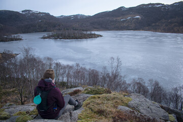 Fototapeta premium Hiker with Samoyed husky dog ​​looking at frozen lake and fjord in Rogaland Norway