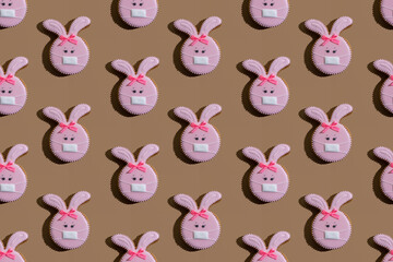 Food background. Seamless pattern. Covid protection. Disease prevention. Conceptual art. Bunny gingerbread cookies pink icing medicine mask ornament isolated on beige.