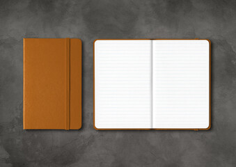 Leather closed and open lined notebooks on dark concrete background