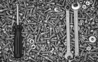screwdriver and two wrenches against the background of scattered fasteners
