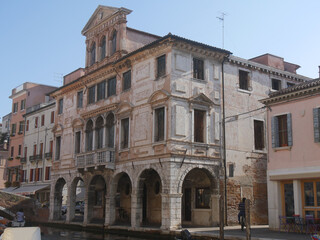 Fototapeta na wymiar Chioggia, Grassi Palace with baroque facade with balconies and a triangular pediment along Vena Canal