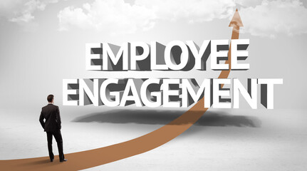 Fototapeta premium Rear view of a businessman standing in front of EMPLOYEE ENGAGEMENT inscription, successful business concept