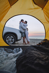 couple meeting sunrise at sea beach. view through camping tent