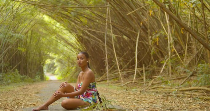 Model sits at the trail of an epic scenic bamboo cathedral on the Caribbean island of Trinidad