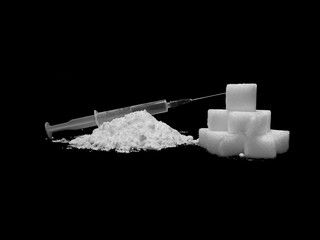 Injection syringe on cocaine drug powder pile and lump sugar cubes on black background, sugar is more addictive than cocaine, isolated cubes of white sugar and cocaine on black background