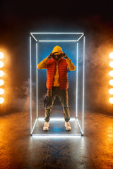 Stylish rapper poses in illuminated cube - obrazy, fototapety, plakaty