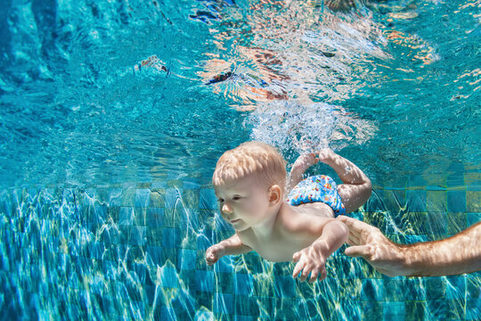 Happy people dive underwater with fun. Funny photo of father, child in aqua park swimming pool. Family lifestyle, kids water sports activity, swimming lesson with parents on summer holiday