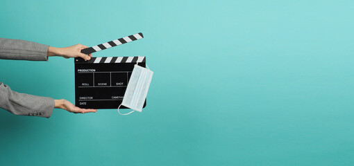 Hands with grey suit and hold black Clapper board or movie slate with face mask. it use in video...