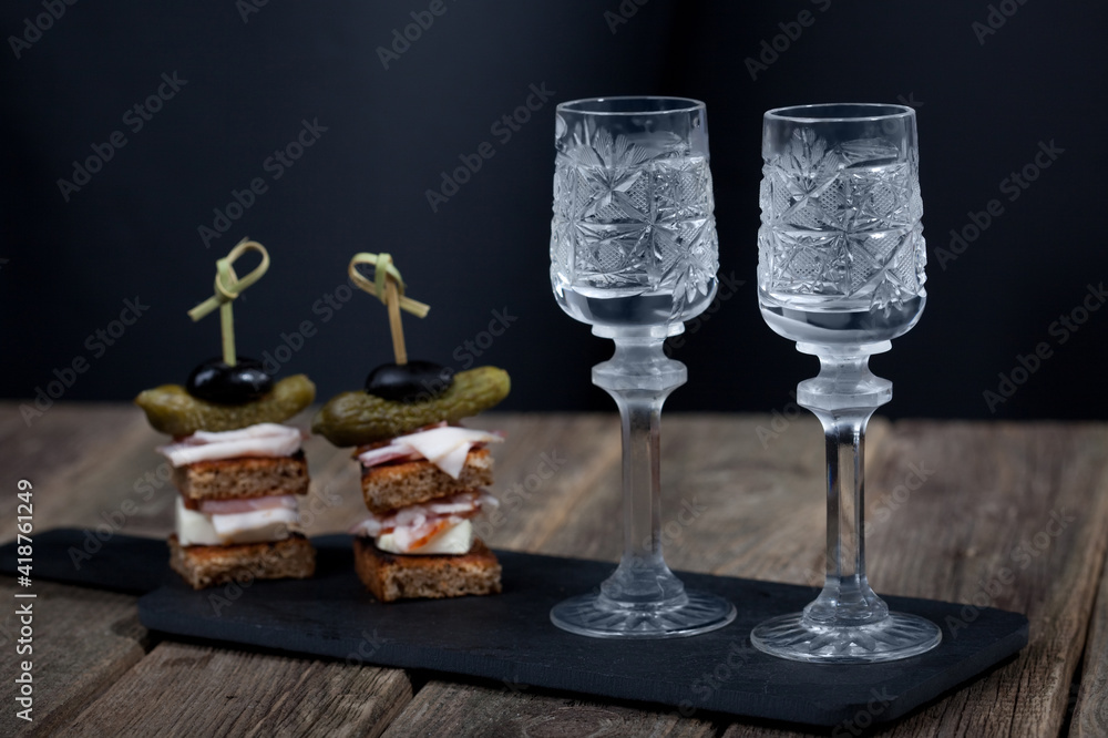 Wall mural two glasses of vodka on a black shale stand on a black background