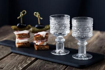 vodka in glasses on black shale on a wooden table