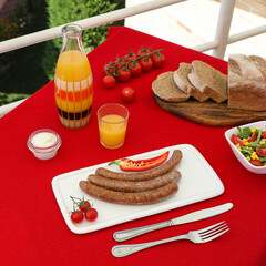 Grilled sausages on serving table with bread and fresh salad. Delicious summer homemade dinner. Picnic.