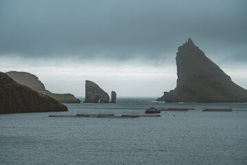 Faroe Islands Aerial drone view of Drangarnir cliff and Tindholmur islands. Taken during intense clouds in summer with dark blue water of atlantic ocean and and lush greens. Faroe Islands, Denmark