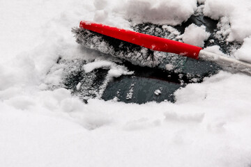 winter safety while driving the car - a person cleaning the snow from the windshield of a car