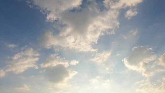 Golden sun light ray flare n bokeh sunbeam shining through puffy fluffy dark gray cloud n cumulus white cloudscape on colorful sunny sunrise or sunset pastel blue sky, 4k cinemagraphs b-roll TimeLapse