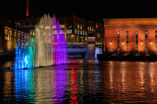 Colourful lighted fountain with industrial brick buildings in background