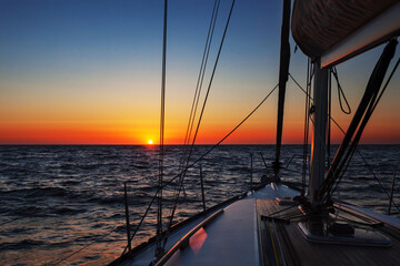 Sailing boat at open sea at colorful sunset