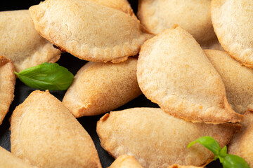 Margarita Margherita pizza parcels pockets filled with tomato, mozzarella cheese and basil served on black slate board with marinara sauce and olives. Party finger food