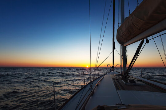 Sailing boat at open sea at sunset