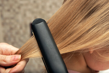 Hair straightening with an iron. Hairstyle at home. Baby hairstyle.