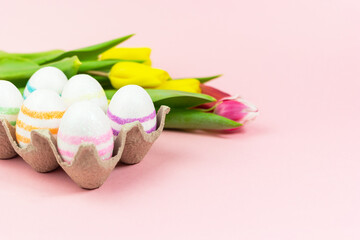 Easter painted eggs with tulips on a pink background. Copy space. Easter celebration concept