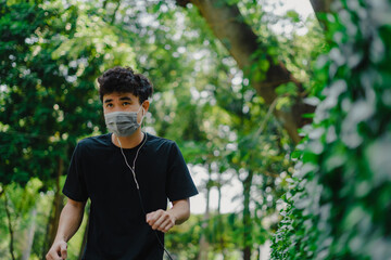 Sporty young asian man wearing face mask while jogging in park.