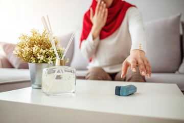 Obraz na płótnie Canvas oung woman treating asthma with inhaler. Asthmatic Muslim woman using inhaler. Girl suffering asthma attack reaching inhaler. Mid adult Muslim woman using asthma inhaler