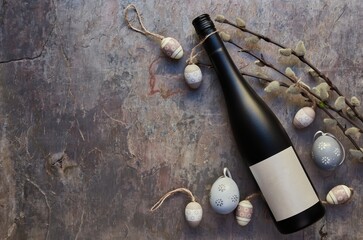Top view of wine bottle with blank white label. Easter decorations on dark stone table background. Wine bottle mockup. Copy space.
