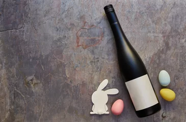  Top view of wine bottle with blank label and Easter eggs and white bunny on dark stone table background. Wine bottle mockup. Copy space for text. © a.dl