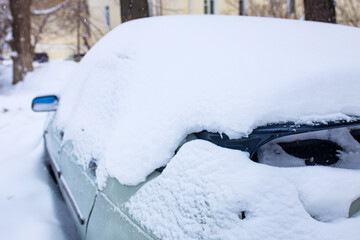 car under snow during winter snowfall in street outdoor in Russia