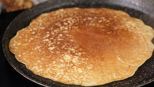 French crepes cooking on a frying pan. Russian blini, thin pancakes