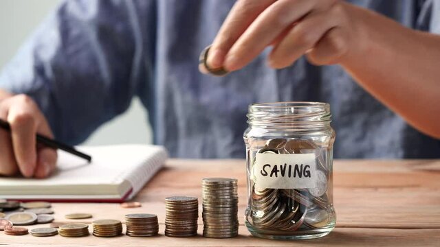 Businessman hand putting coins in glass jar. Concept of saving money, financial planning, investment, growth management, business, finalcial.