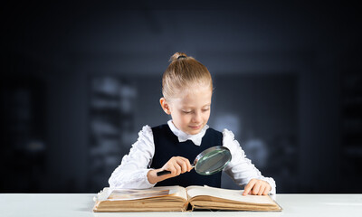 Little girl sitting at desk with magnifier