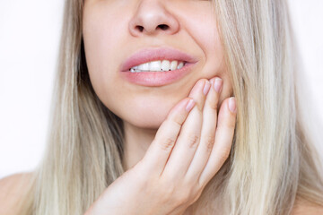 Cropped shot of a young beautiful blonde woman with a toothache holding her cheek isolated on white...