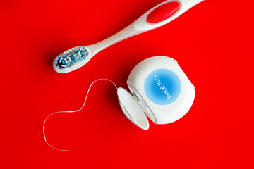 A blue toothbrush and dental floss on a red background. Dental care concept. Oral hygiene and health