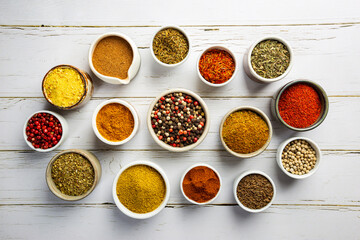 Herbs and spices in bowels over white wooden background. Top view with copy space