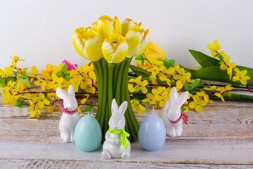 A tulip-shaped candle with Easter eggs, Easter bunny and a bouquet of flowers.