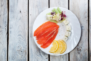 slices of salmon cream cheese slice lemon fresh salad serving on a round plate on a white wooden background top view copy space